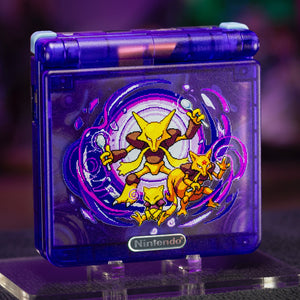 A translucent purple Nintendo 3DS handheld game console with a custom graphic of Eevee and its offspring on the front cover, displayed on a clear acrylic stand against a dark, blurred background.